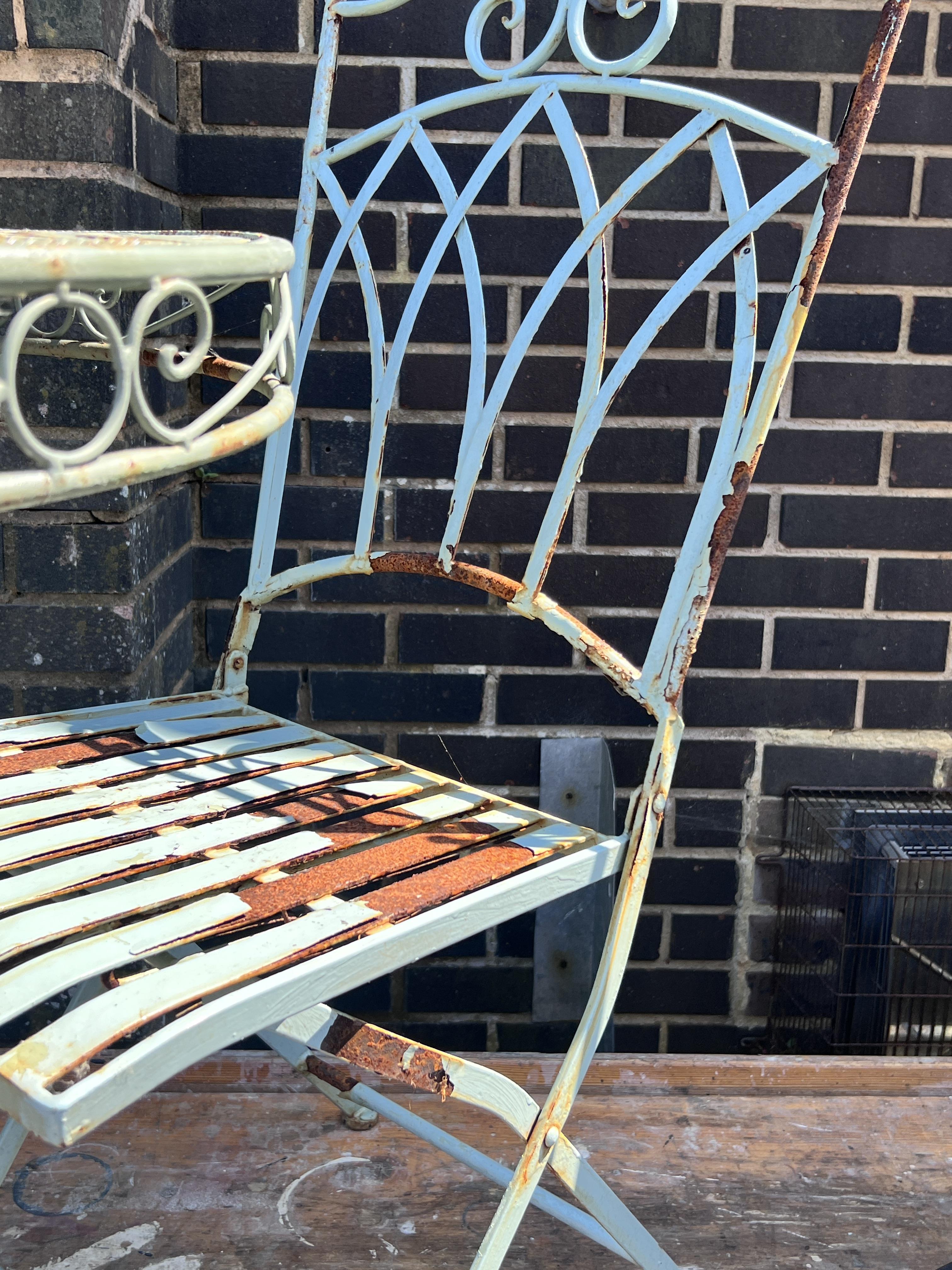 A circular painted metal garden table, diameter 70cm, height 74cm, and two chairs